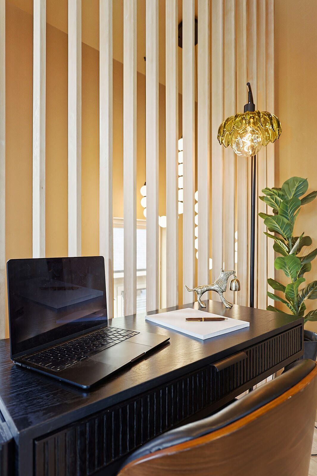 A laptop on a desk with a lamp, a decorative item, and a plant.