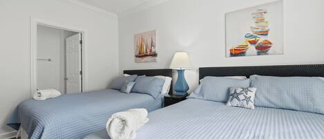 A hotel room with two beds, a nightstand, a lamp, and artwork on the walls.