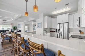 A modern kitchen with white cabinetry, stainless steel appliances, and a central island.