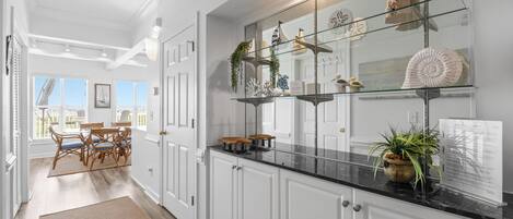 A kitchen with white cabinets, a black countertop, and decorative items on shelves.