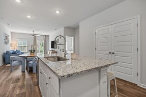 A modern kitchen with granite countertops, white cabinetry, and a central island.