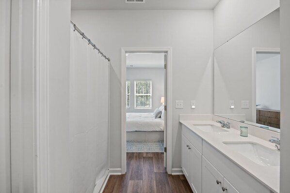 A bathroom with a shower, a double sink vanity, and a mirror.