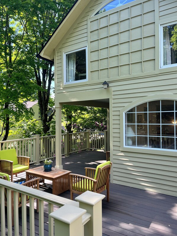 A covered deck with outdoor furniture, a pergola, and a view of a house with a large window.