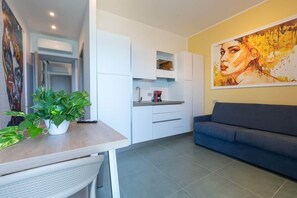 A modern living space with a dining area, kitchenette, and a large painting on the wall. - Alexandr Azure House (Pizzo)