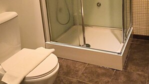 A bathroom with a glass-enclosed shower, a toilet, and tiled flooring. - Happy@chiadosuites12 (Lisboa)