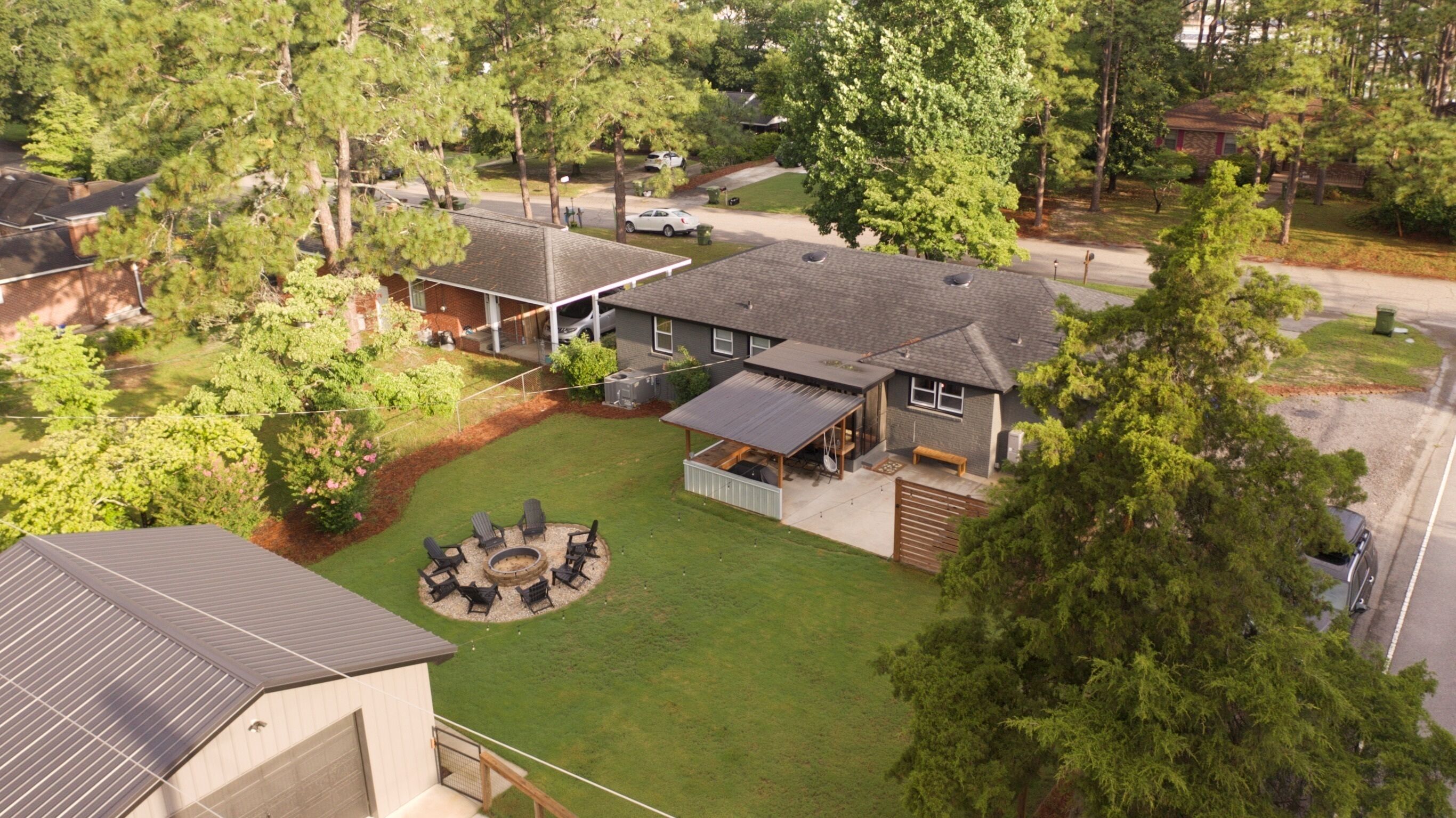 A residential property with a covered patio, a lawn with outdoor seating, and a garage.
