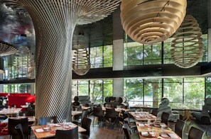 A modern restaurant interior with high ceilings, large windows, and contemporary lighting fixtures.