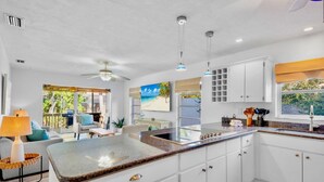A spacious kitchen with white cabinets, a granite countertop, and a ceiling fan. - Paradise Palms: Pool, Game Room, & Minutes to Siesta Key Beach! (Siesta Key)