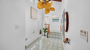 A hallway with a ceiling fan, a staircase, and artwork on the walls. - Paradise Palms: Pool, Game Room, & Minutes to Siesta Key Beach! (Siesta Key)