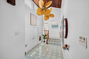 Ein Flur mit Deckenventilator, einer Treppe und Kunstwerken an den Wänden.