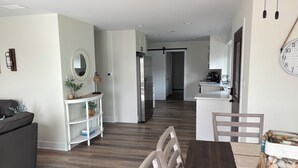 Eine moderne Küche mit weißen Schränken, einem Holzespeise Tisch und einer Sitzecke mit einem dunklen Sofa und einem weißen Beistelltisch.