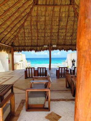 A beachside lounge with wooden furniture, a thatched roof, and a view of the ocean. -  Cancún Caribe Soul studio /walk on beach/ Top Location (Cancún)