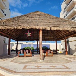 A covered outdoor seating area with a thatched roof, wooden benches, and a decorative star hanging from the ceiling. -  Cancún Caribe Soul studio /walk on beach/ Top Location (Cancún)