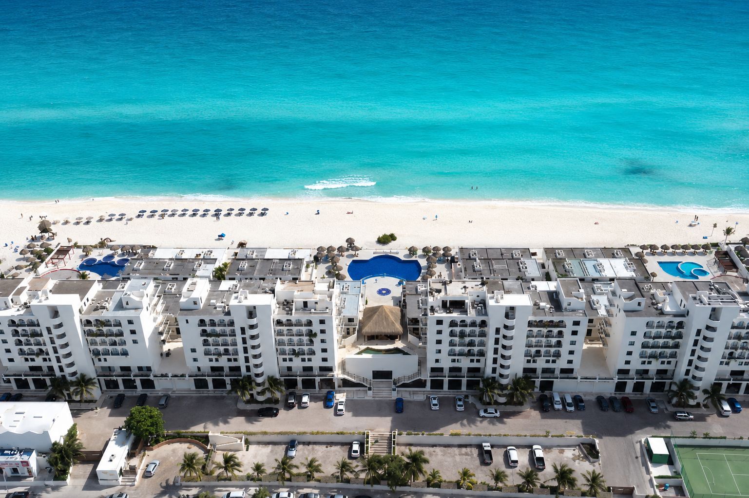 A resort with multiple buildings, a beach, and a swimming pool.