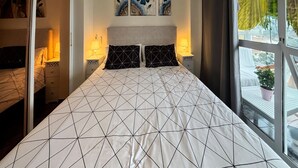 Un lit avec une couvre-lit à motifs géométriques, des lampes de chevet, une table de chevet et une fenêtre donnant sur un paysage agréable.