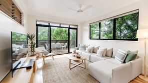 A spacious living room with a large sofa, coffee table, and a dining area with chairs and a table. - Unit 1, 9 Hill Street, Sunshine Beach (Sunshine Beach)