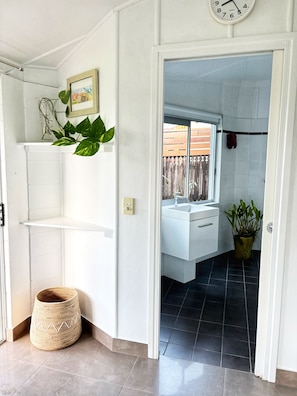 A modern bathroom with a white sink, a potted plant, and a clock on the wall. - The Buddha Studio, modern & private, moments from Cairns cultural hub & airport. (Whitfield)