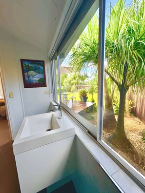A bathroom with a white sink, a window, and a painting on the wall. - The Buddha Studio, modern & private, moments from Cairns cultural hub & airport. (Whitfield)