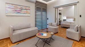 Quarto moderno com sofá, poltronas, uma mesinha de centro e uma grande pintura abstrata.
