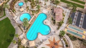 Vue aérienne d’un complexe hôtelier doté de plusieurs piscines, d’une terrasse en forme d’étoile et d’un parking.