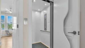 Ein moderner Aufzug mit Bedienfeld, Glastür und Metallhandlauf.