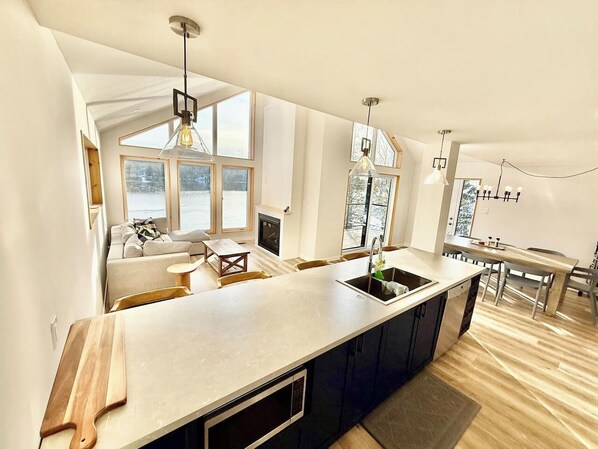 A modern kitchen with a large island, built-in appliances, and large windows. - Muskoka Retreat on Bay Lake (Emsdale)