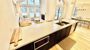 Una cocina moderna con una isla grande, electrodomésticos integrados y ventanas amplias.