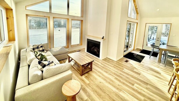 Un salón espacioso con chimenea, ventanas grandes y vistas al agua.