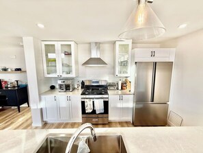 Una cocina moderna con gabinetes blancos, electrodomésticos de acero inoxidable y una isla central con pileta.