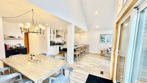 Una cocina moderna con comedor, piso de madera y un ventanal grande.