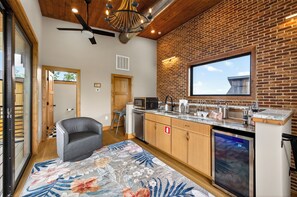 A modern kitchen with a brick wall, wooden ceiling, and a large window. - Brand-New Retreat | Rooftop Deck, Sauna, Hot Tub, Game Room, Mountain Views (Sevierville)