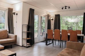 Ein modernes Wohnzimmer mit einer Couch, einem Couchtisch, einem Essbereich mit Stühlen und einem Bücherregal.