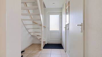 Ein Flur mit Treppe, einer Tür und Fliesenboden.