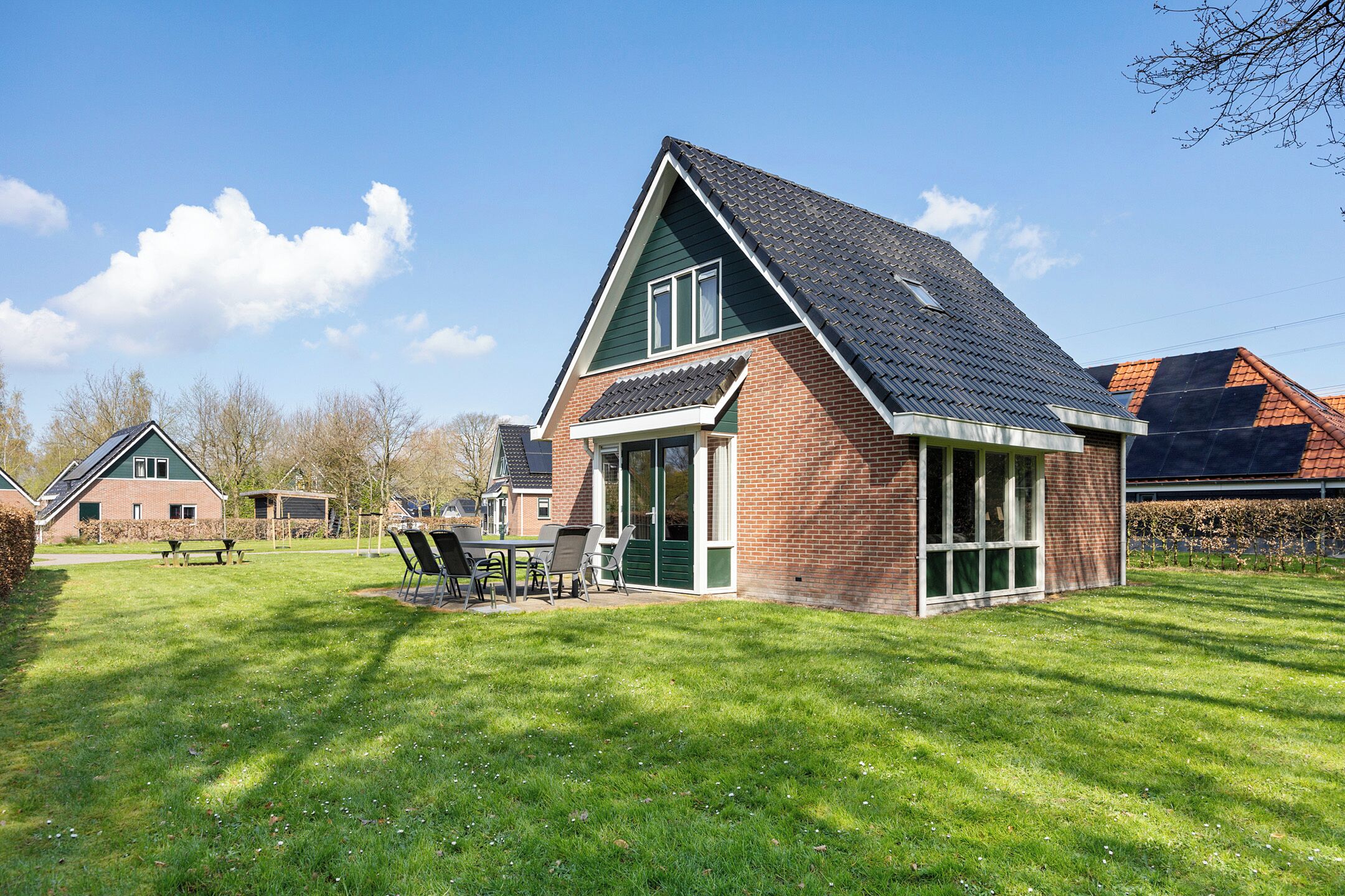 A house with a sloped roof, a brick exterior, and a patio with outdoor furniture.
