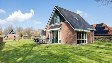 A house with a sloped roof, a brick exterior, and a patio with outdoor furniture.