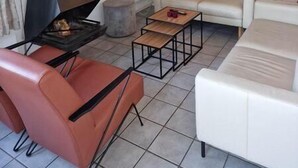 Een woonkamer met een open haard, een bank, een televisie en een raam met planten.