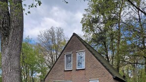 Een huis van baksteen met een schuin dak, twee ramen en een deur.