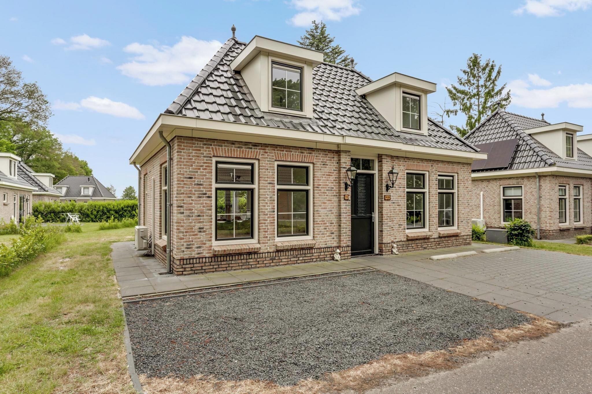 A two-story brick house with a sloped roof, large windows, and a front door.
