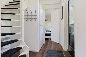 Un pasillo estrecho con una escalera, una cama y una puerta que da a otra habitación.