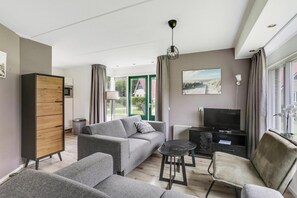 Ein modernes Wohnzimmer mit einem grauen Sofa, einem schwarzen Couchtisch und einem Fernsehschrank.
