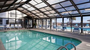 A swimming pool with a glass roof, lounge chairs, and a view of the city. - Relax in this premier beachfront 1-bedroom condo in Carolina Beach 0501 (Carolina Beach)