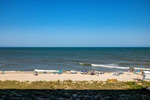 A beach with people, umbrellas, and lounge chairs. - Oceanfront bliss awaits at 0506 Seaside Escape in Carolina Beach! (Carolina Beach)