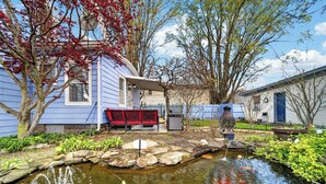 A residential property with a pond, a red bench, and a house with a blue exterior.