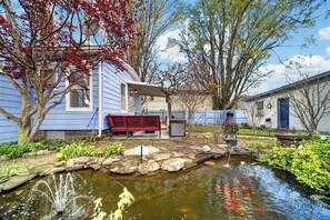 A residential property with a pond, a red bench, and a house with a blue exterior.