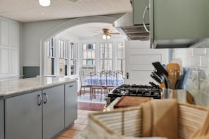 A kitchen with a gas stove, cabinets, and a dining area with a table and chairs.
