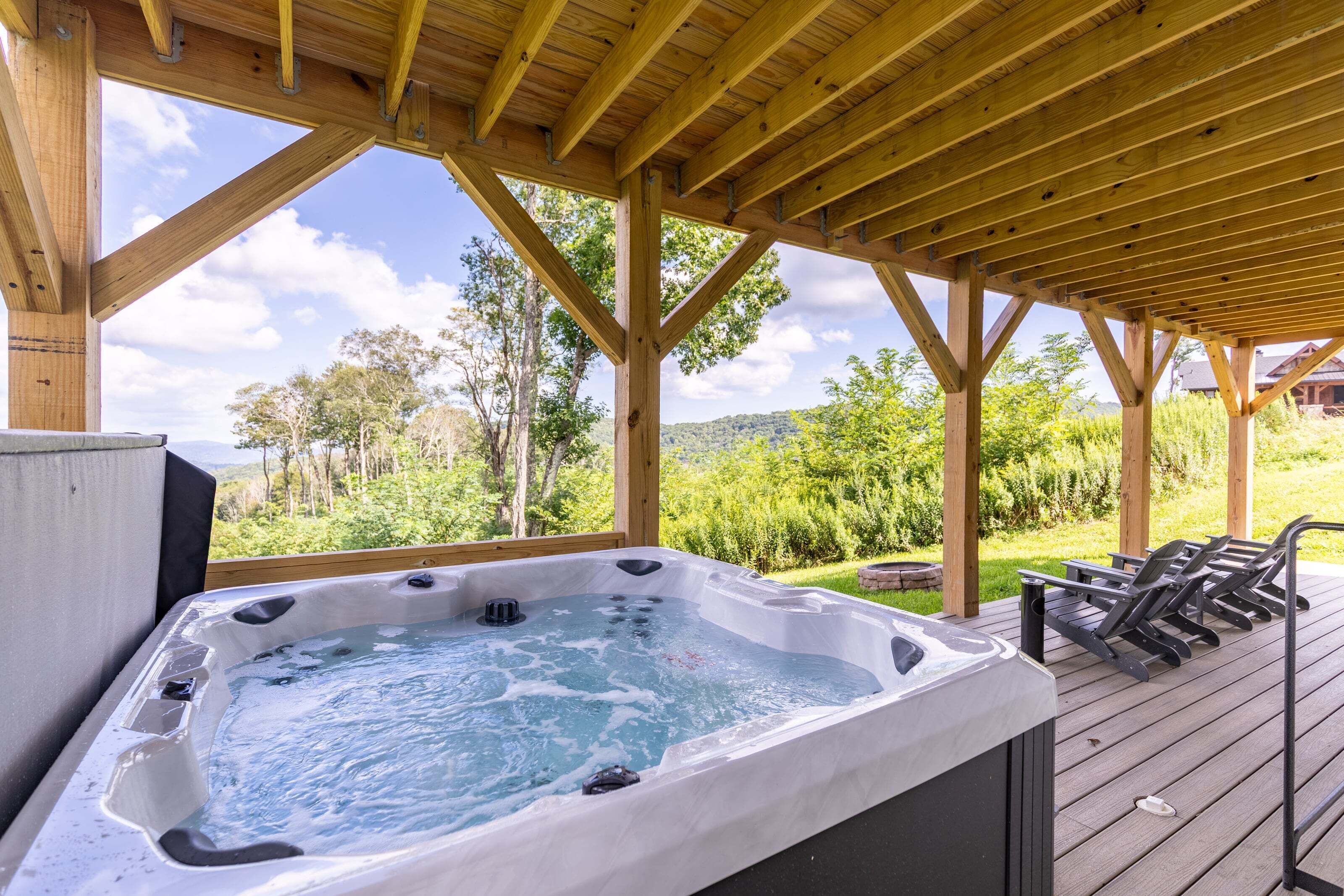 Un bain à remous installé sous une pergola en bois, offrant une vue sur un paysage luxuriant.