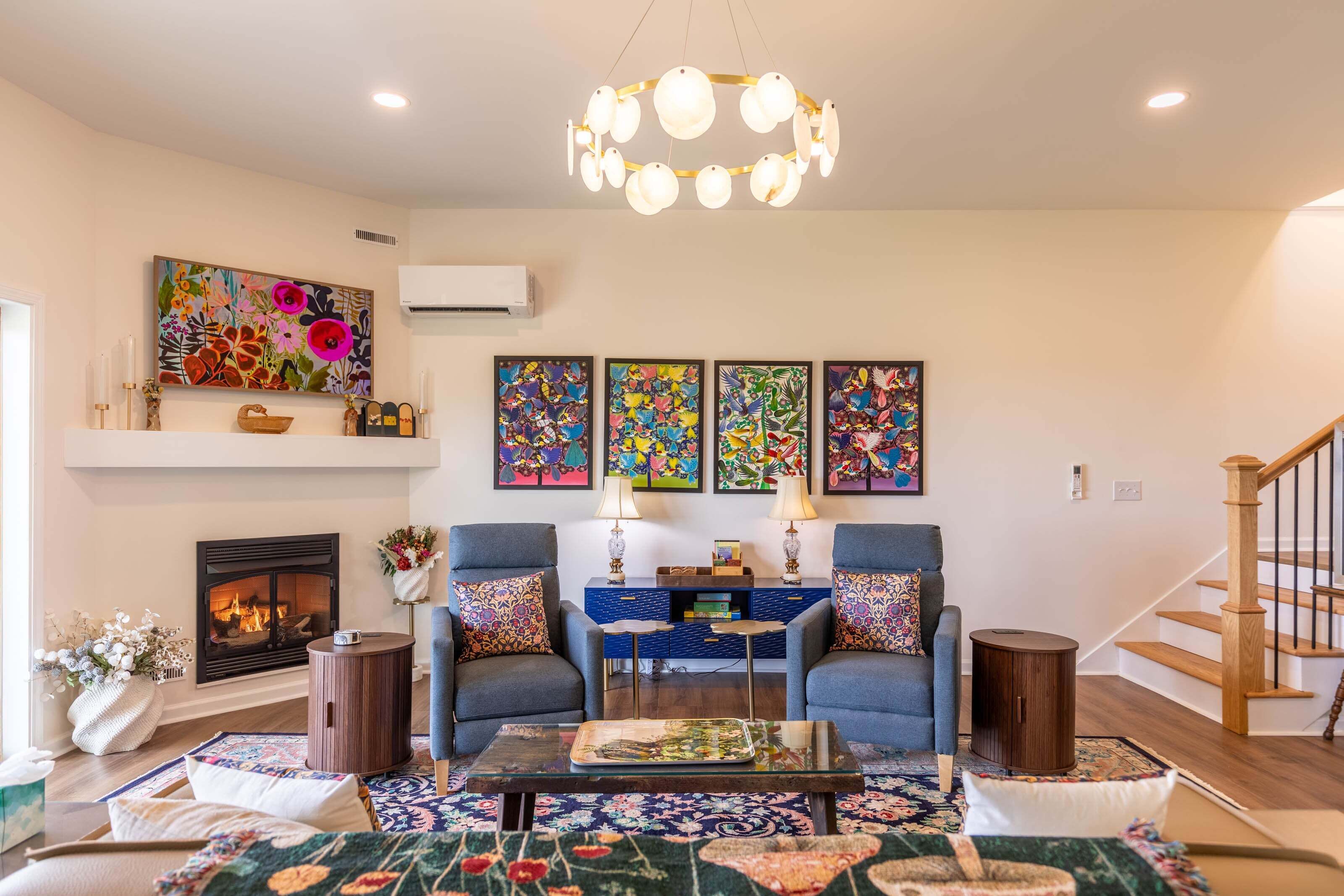 A living room with a fireplace, two armchairs, a coffee table, and a staircase.