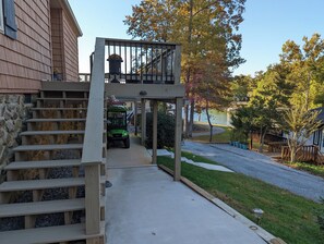Il s’agit d’une propriété résidentielle dotée d’un escalier en bois menant à un espace extérieur couvert, d’une pelouse et d’une vue sur un lac.