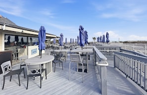 A deck with outdoor seating, umbrellas, and a sign indicating a beach club. - Oceanview Resort-Pool, Pickleball & Beach Access (Hilton Head Island)