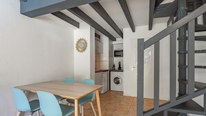 Un comedor con una mesa y sillas, una cocina al fondo y una escalera.